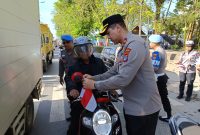 Waka Polres Tanah Bumbu, Kompol Apriyansa SIK Saat Bagikan Bendera pada pengendara di Jalan Raya Batulicin