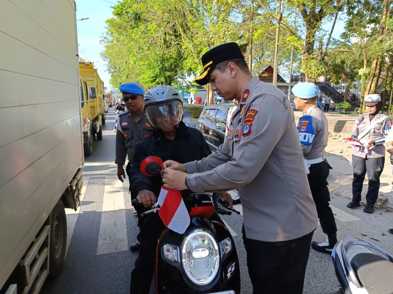 Waka Polres Tanah Bumbu, Kompol Apriyansa SIK Saat Bagikan Bendera pada pengendara di Jalan Raya Batulicin